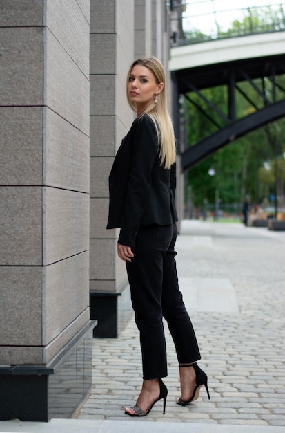 Een blonde vrouw in een zwart pak in de city.businesswoman op een wandeling.