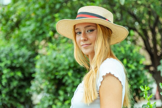 Foto een blonde vrouw met een strohoed staat in een park.