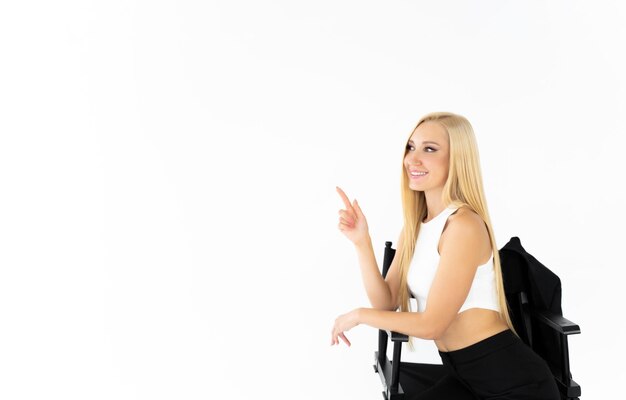 Een blonde vrouw zit op een stoel en wijst naar rechts.