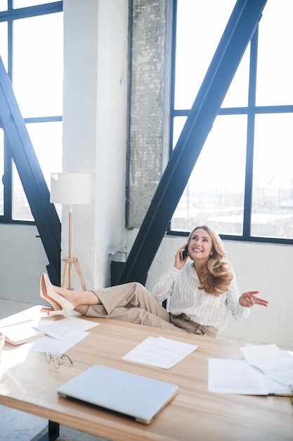 Een blonde zakenvrouw in haar kantoor aan de telefoon