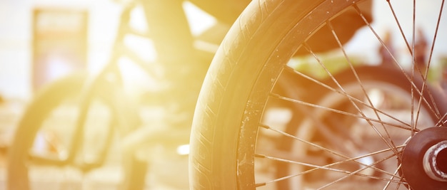 Een BMX-fietswiel tegen de achtergrond van een vage straat met fietsruiters. Extreme sporten concept