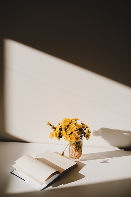 Een boek en een bos gele paardebloemen op tafel