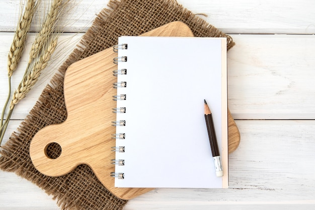 Een boek Kladblok papier over het hakken van snijplank en tafellaken op witte tafel