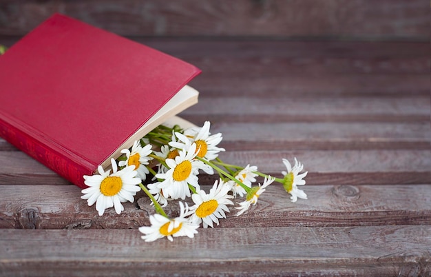 Een boek met een boeket madeliefjes erop op een houten tafel