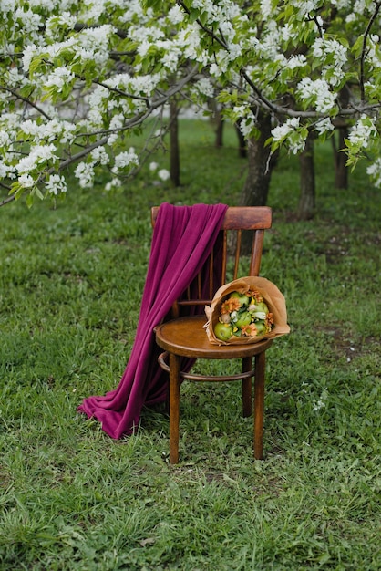 Een boeket bloemen en appels ligt op een stoel in de zomertuin