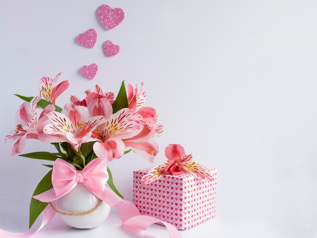 Een boeket bloemen en een cadeautje staan naast een doosje met een hartje erop.