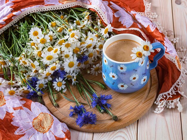 Een boeket bloemen en een kopje koffie met een blauw-witte mok koffie.