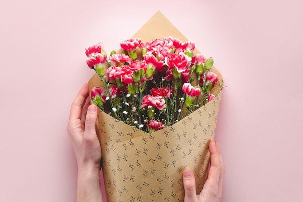 Een boeket bloemen in ambachtelijk papier op een roze achtergrond.