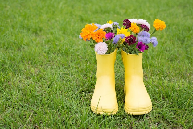 Een boeket bloemen in gele laarzen op een achtergrond van groen gras