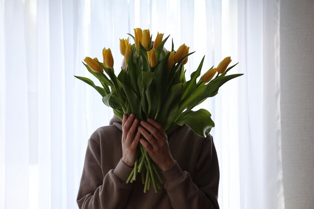 Een boeket gele tulpen in de hand