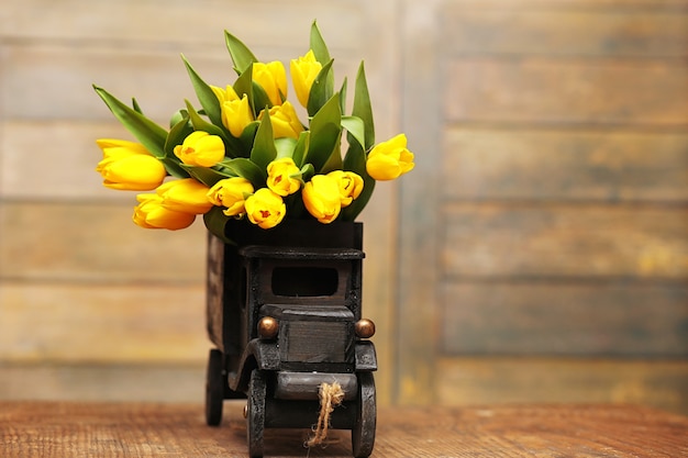 Een boeket gele tulpen in een vaas op de vloer. Een cadeau voor een vrouwendag van gele tulpenbloemen. Mooie gele bloemen in een vaas aan de muur.