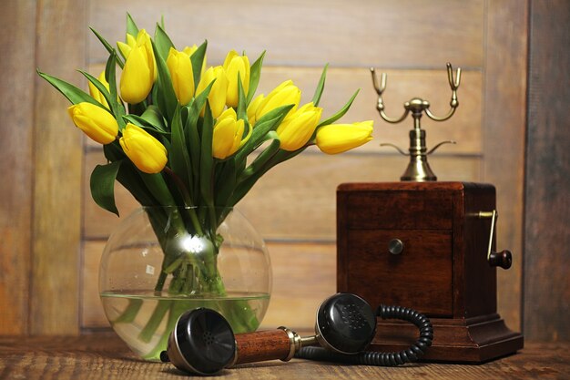 Een boeket gele tulpen in een vaas op de vloer. Een cadeau voor een vrouwendag van gele tulpenbloemen. Mooie gele bloemen in een vaas aan de muur.