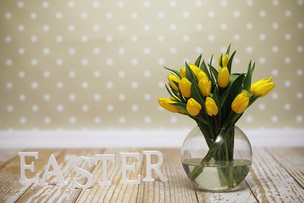 Een boeket gele tulpen in een vaas op de vloer. Een cadeau voor een vrouwendag van gele tulpenbloemen. Mooie gele bloemen in een vaas aan de muur.