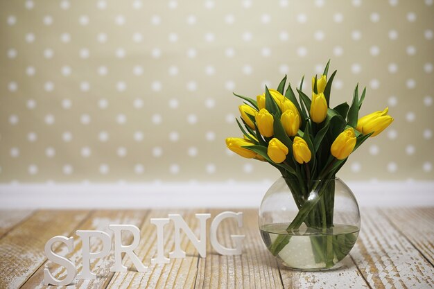 Een boeket gele tulpen in een vaas op de vloer. Een cadeau voor een vrouwendag van gele tulpenbloemen. Mooie gele bloemen in een vaas aan de muur.