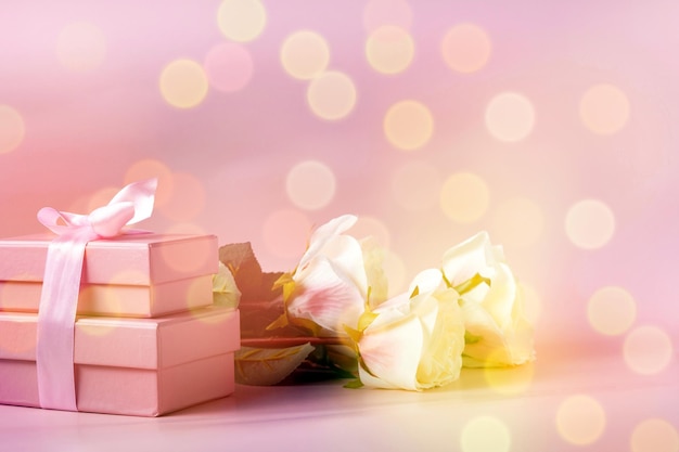 Een boeket rozen en roze geschenkdozen gebonden met een lint op een lichte achtergrond een kopie van de ruimte defocus