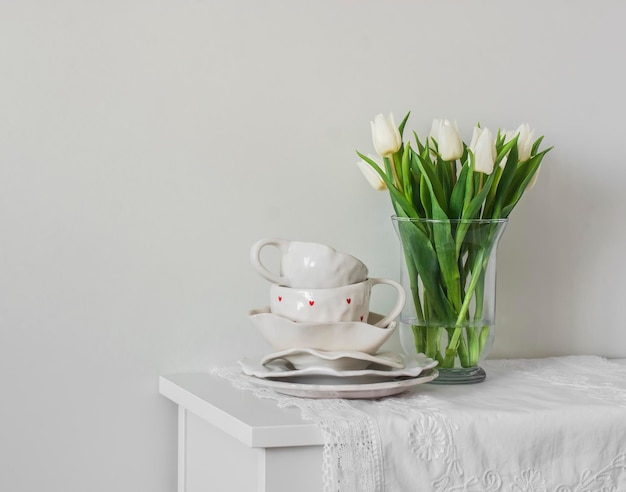 Een boeket tulpen in een glazen vaas en retrostyle keramische servies op een witte kombuis