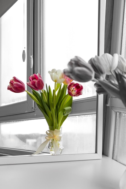 Foto een boeket tulpen in een glazen vaas met een strik kleurweergave van zwarte en witte bloemen