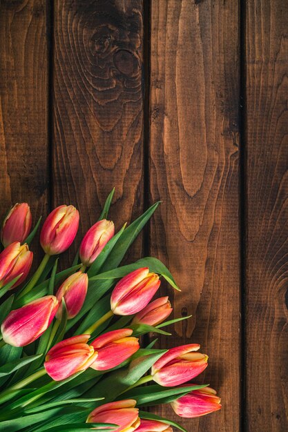 Een boeket tulpen ligt op een bruine houten ondergrond