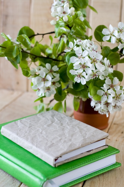 Een boeket van bloeiende takken van fruitbomen en een oud notitieblok op ongeverfd houten