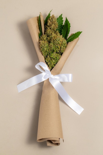 Foto een boeket van cannabisbloemen en wietgewrichten met een wit lint aan het handvat
