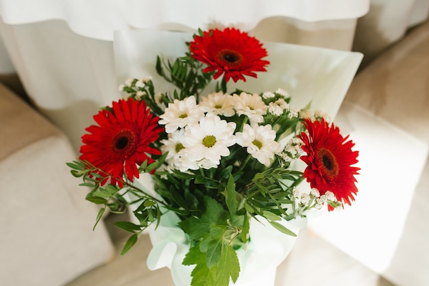 Een boeket van mooie rode gerbera's en witte chrysanten in een vaas