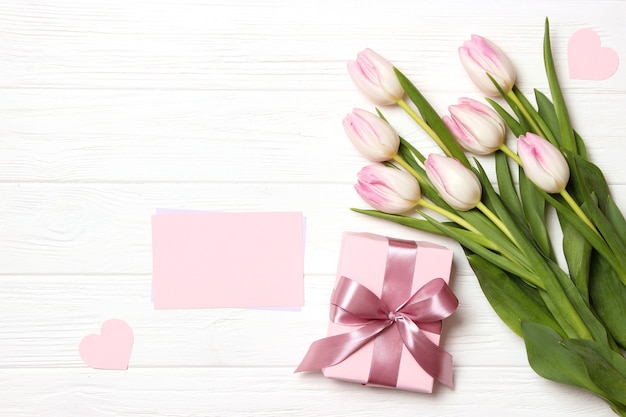 Een boeket van mooie tulpen en een geschenk op een houten achtergrond bovenaanzicht