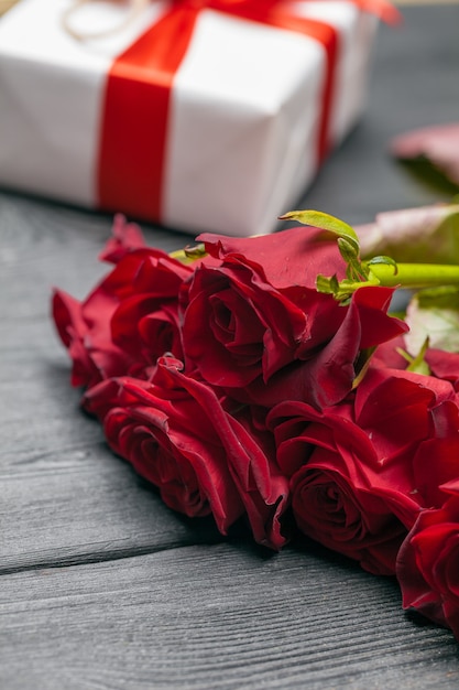 Een boeket van rode rozen, cadeau en harten op tafel. Concept Vrouwendag of St. Valentine. Kopieer ruimte