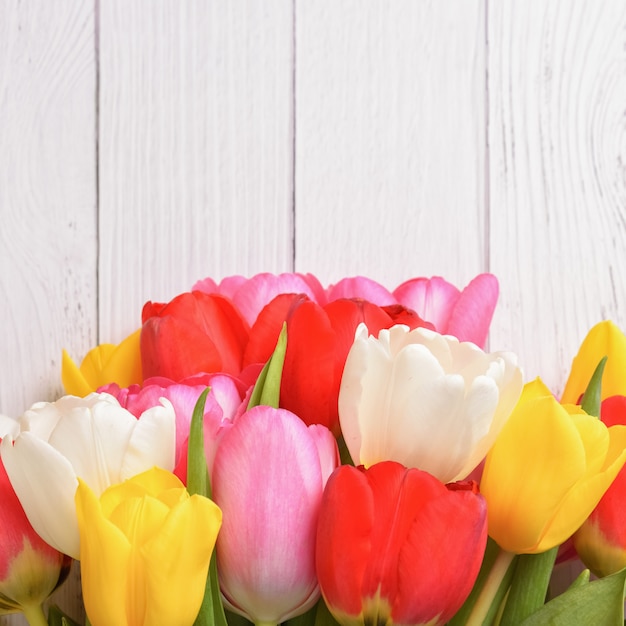 Een boeket van verse veelkleurige tulpen op hout