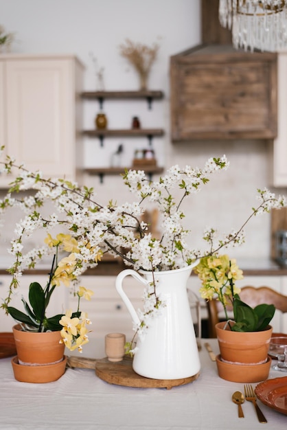Een boeket van witte lentebloemen op takken in een vaas op de keukentafel Scandinavische stijl van het interieur en de inrichting van het huis