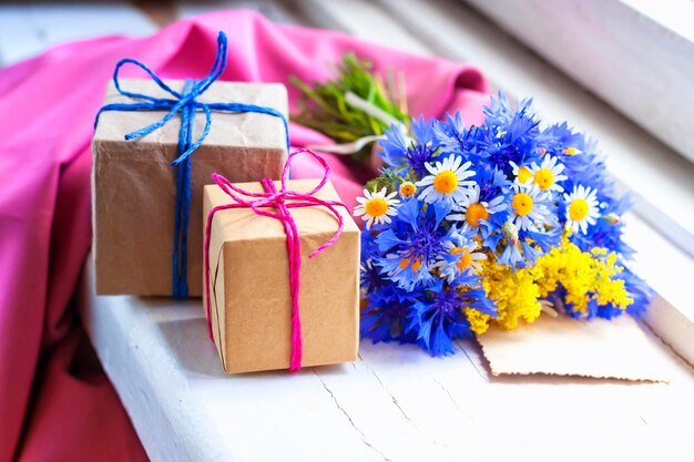 Een boeket veldbloemen en ingepakte cadeautjes op de vensterbank.