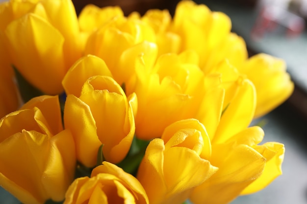 Een boeket verse gele tulpen in een vaas op een tafel bij het raam