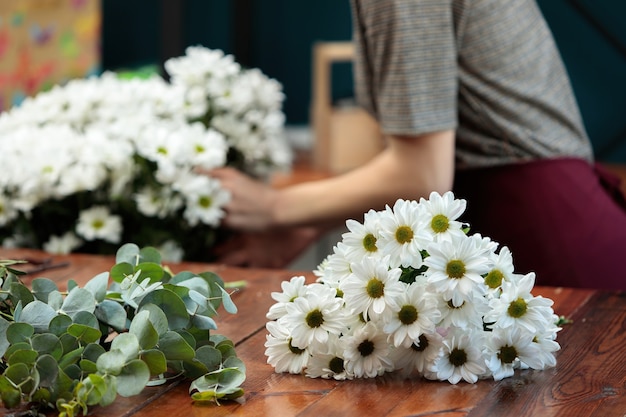 Een boeket witte chrysanten ligt op een houten tafel.