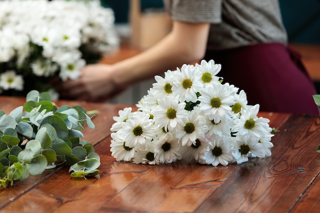 Een boeket witte chrysanten ligt op een houten tafel.