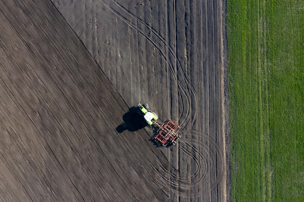 Een boer in een tractor bereidt land voor met een zaaimachine als onderdeel van het voorzaaien aan het begin van het lentelandbouwseizoen op landbouwgrond