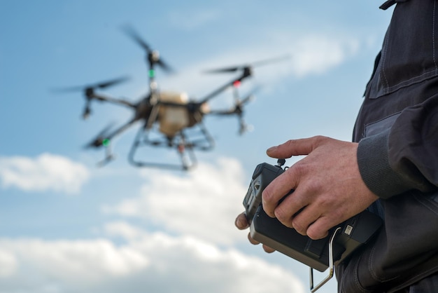 Een boer met een afstandsbediening in zijn handen om met een agrodrone in de lucht te spuiten, de nieuwste technologieën voor bemesting richten zich op handen