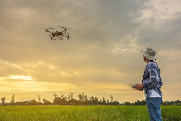 Een boer met een pet staat in een weelderig tarweveld en bestuurt een drone die boven de rand vliegt Mannetje bestuurt de apparatuur Landbouwtechnologieën