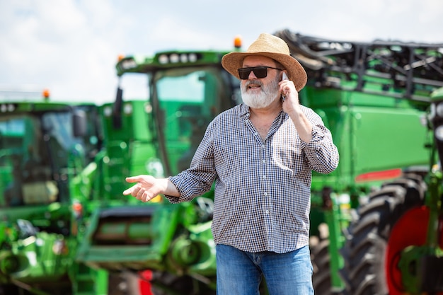 Een boer met een tractor, combineer op een veld in zonlicht. Zelfverzekerde, heldere kleuren