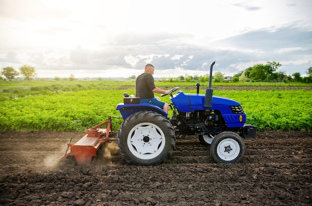 Een boer op een tractor cultiveert een veld Werk op de boerderij Grond frezen Verzachten van de grond voordat nieuwe gewassen worden geplant Landbouw Ploegen Losmaken van oppervlakte landbewerking Mechanisatie in de landbouw