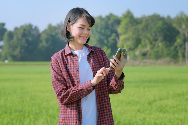 Een boerin in een gestreept shirt poseert met een smartphone in een veld.