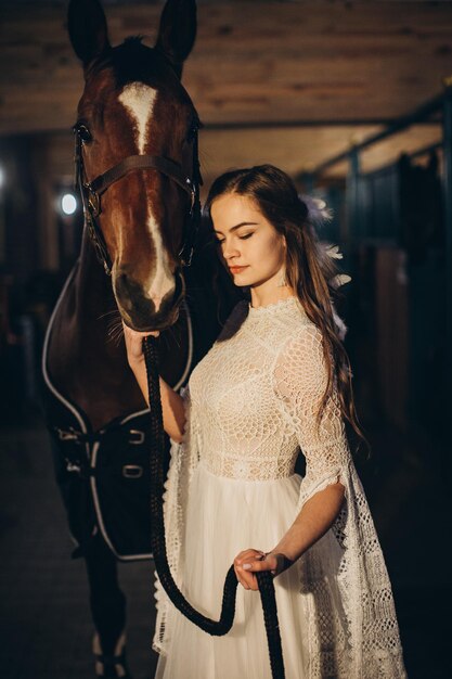 Een boho-bruid poseert met een paard in een stal