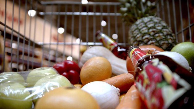 Een boodschappentrolley in de supermarkt die verschillende groenten en fruit en flessen alcohol koopt