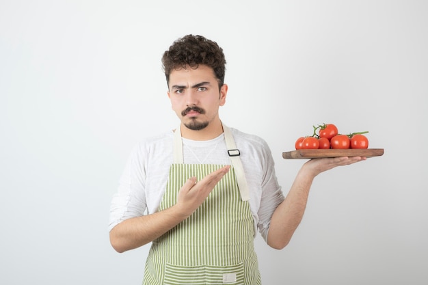 Een boos jonge man met stapel verse tomaten.