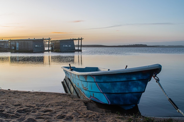 Een boot aan de oever van een meer met een boot op de voorgrond.