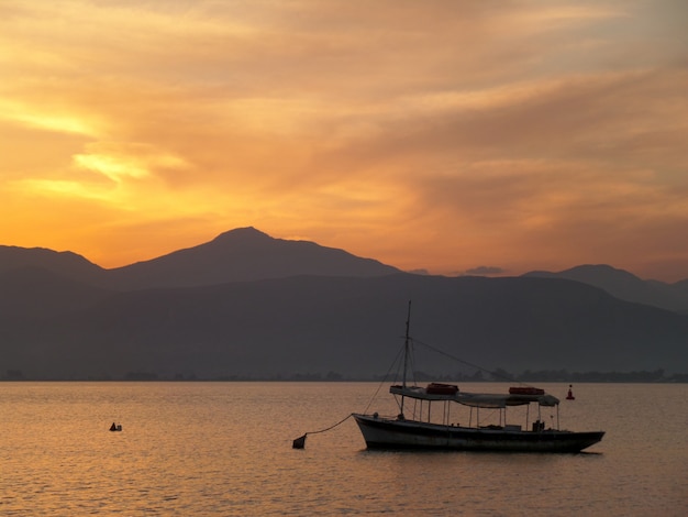 Een boot drijvend op de Egeïsche zee onder mooie gouden hemel na zonsondergang, Nafplio, Griekenland