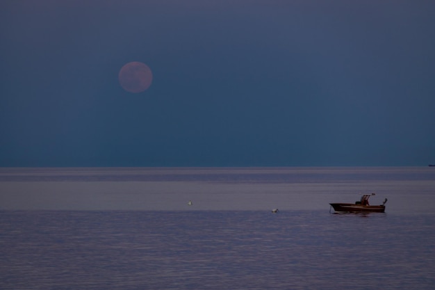 Een boot en een opkomende maan op een mediterraan strand van de Ionische Zee Bova Marina Calabria Italië