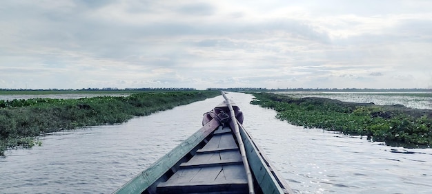 Een boot vaart een rivier af met een groen veld op de achtergrond.