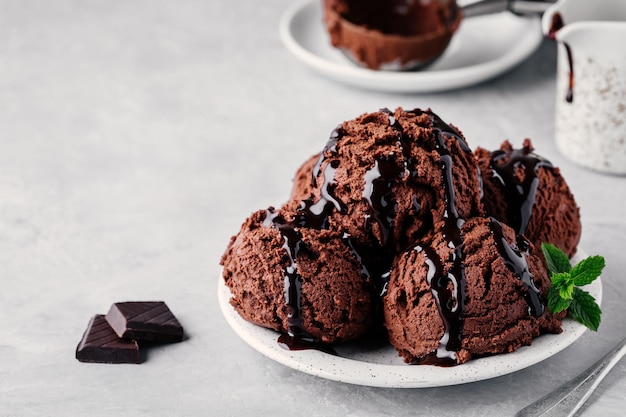 Een bord chocolade-ijslepels met chocoladesaus op lichte achtergrond