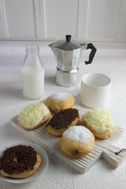 Een bord donuts met op een ervan een witte kop melk.