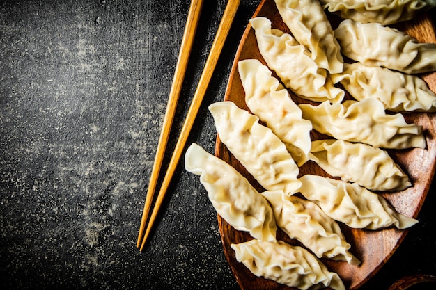 Foto een bord dumplings met houten eetstokjes op een donkere achtergrond.
