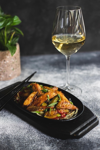 Een bord eten met stokjes en een glas witte wijn.